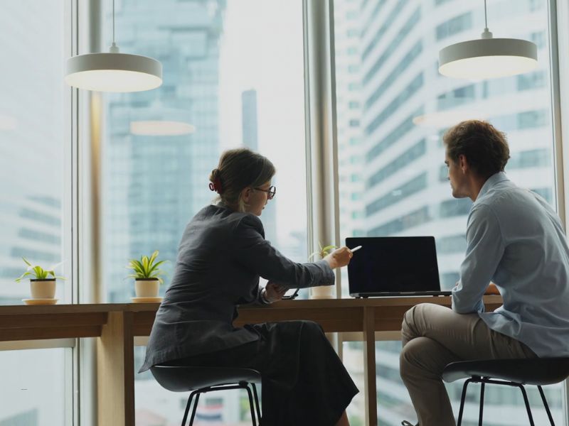 dva poslovna partnera sede i dogovaraju se oko posla koristeći laptop