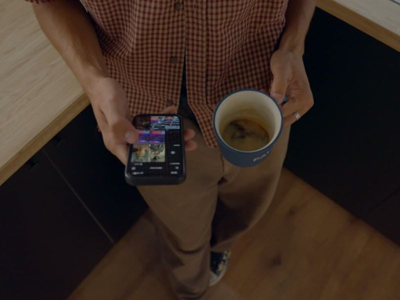 osoba lista društvene mreže i držoi šolju kafe u ruci